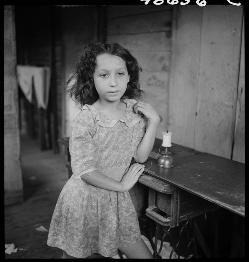 Photo Courtesy of the Delano Collection at Rare Book and Manuscript Library A girl stands by a sewing table with a roll of string. Photo Courtesy of the Delano Collection at Rare Book and Manuscript Library