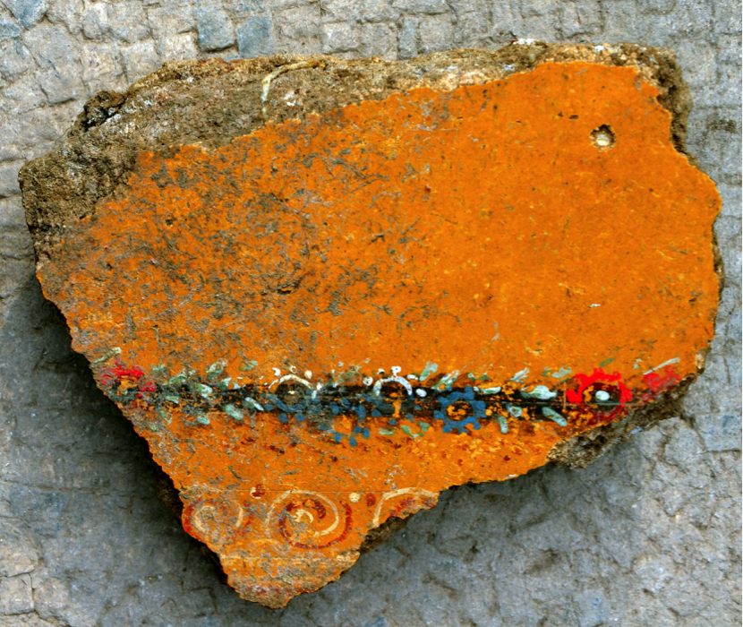 Fragment from the ceiling of the newly excavated building, with vegetal decoration. Photo by D. Nocera Bright orange painted piece of wall