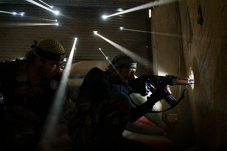 Rebel soldiers hold their position in the Syrian city of Aleppo, a picture that won the feature photography Pulitzer in 2013. Photo by Javier Manzano Two men fire bullets through a hole in the wall