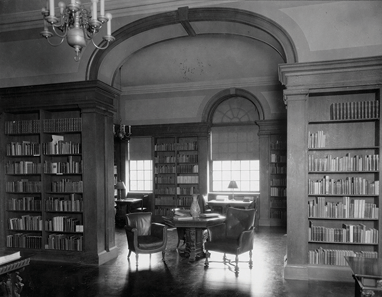 A cozy library with books, a table and two chairs