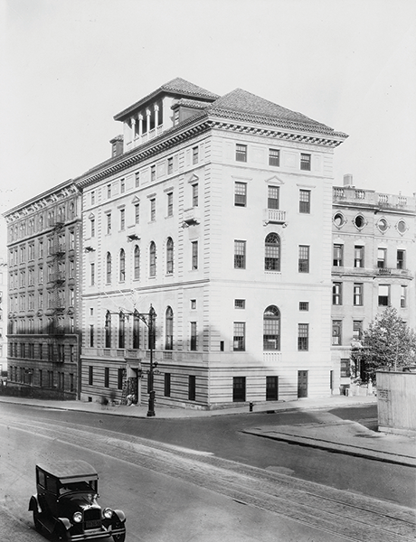 A white building with five stories on the corner of a street