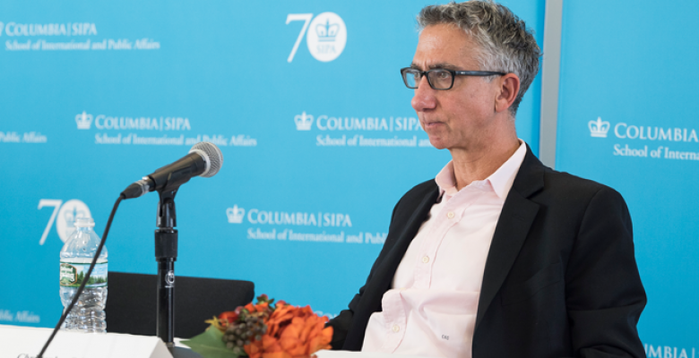 christopher sabatini seated at a table with an aqua background