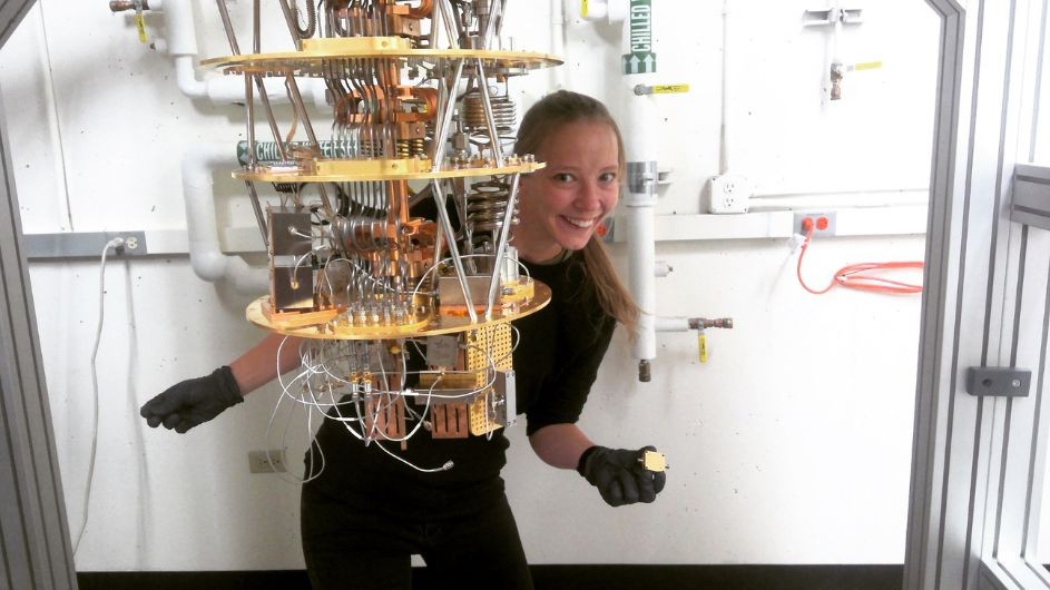 Lana wearing black gloves holding a microresonator that she is getting ready to install into a dilution refrigerator at the University of Colorado Boulder