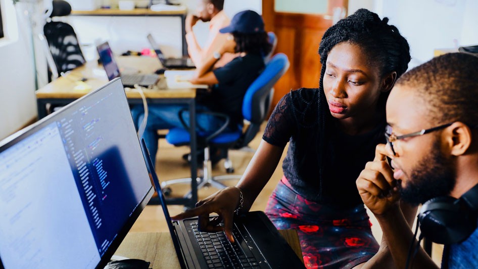 Two people analyzing data on a computer