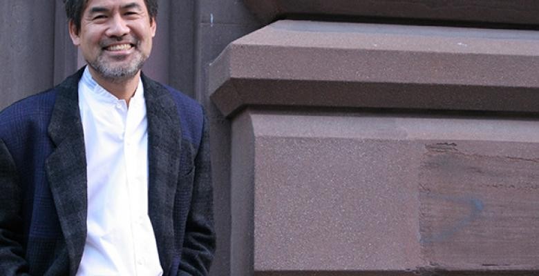 David Henry Hwang stands with hands in pocket wearing a dark blazer and white button down dress shirt