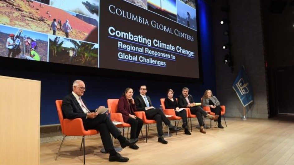 Six people sitting on orange chairs on the stage