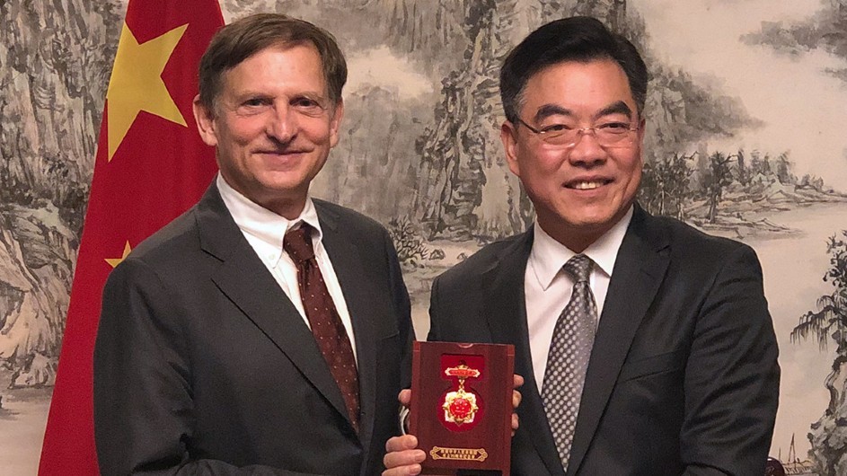 Two men posing for a photo in front of the Chinese flag