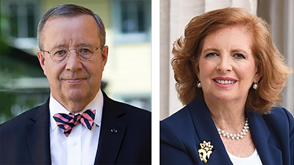 A man wearing a bowtie and a woman wearing a broach and a necklace pose side by side