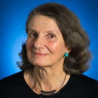 A woman with medium-length brown hair facing forward wearing blue earrings 