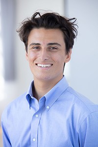 young man with blue shirt and dark hair smiling