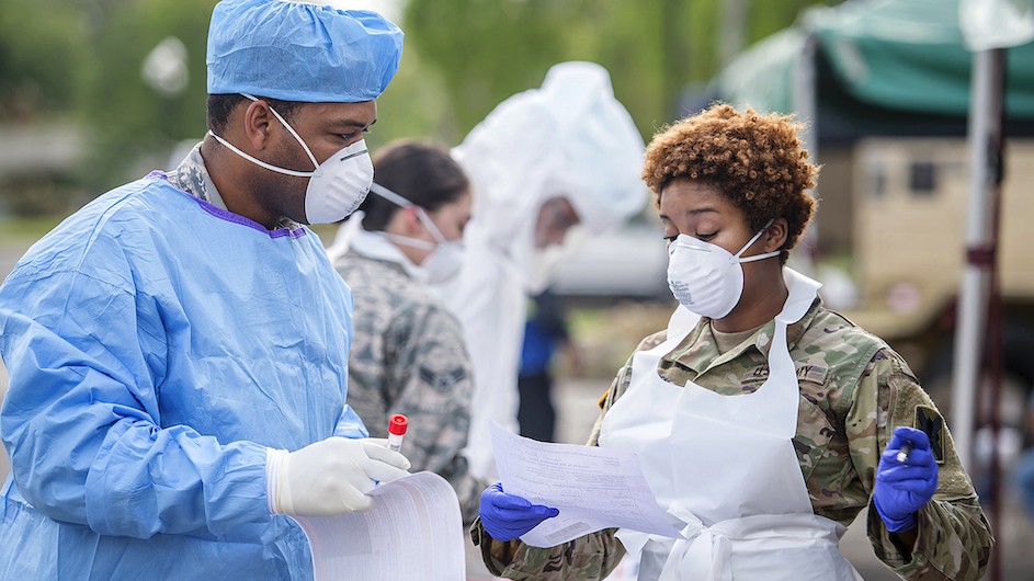 https://blogs.cuit.columbia.edu/cssw-covid19resources/ A man in PPE and a woman in a mask and an apron discussing something outside