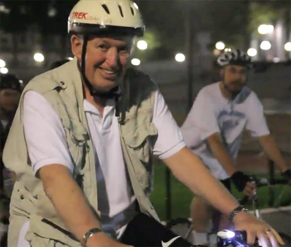 Two men wearing helmets and riding bike 