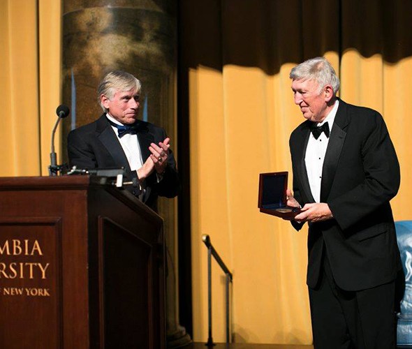 Columbia President Lee C. Bollinger celebrates Jackson receiving the 2016 Alexander Hamilton award. A man clapping at another man receiving an award