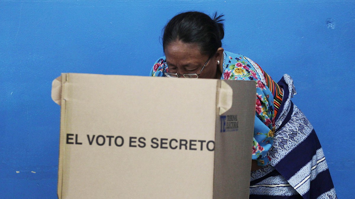 a woman hunched over inside of a makeshift voting booth