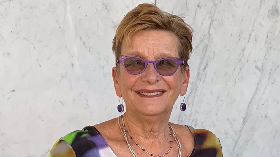 A woman in a colorful shirt, earrings and necklace.