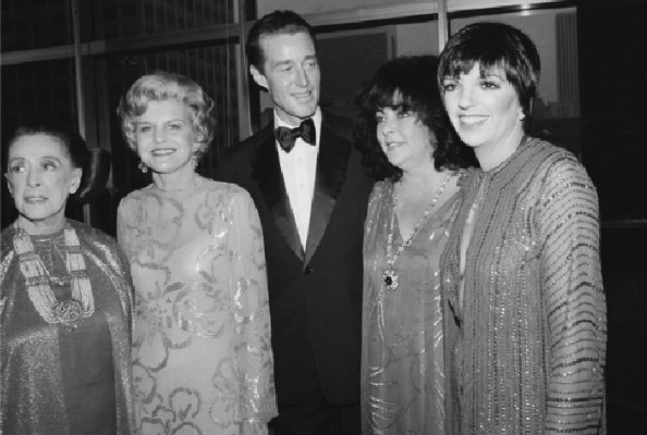 Four women and a man standing and posing for a photo