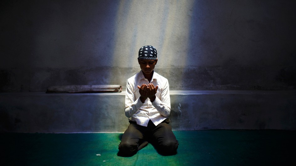 A Nepalese Muslim boy offers Friday prayers during the Muslim holy month of Ramadan in Kathmandu. (Navesh Chitrakar/Reuters) A muslim boy kneeling down and praying under a spotlight