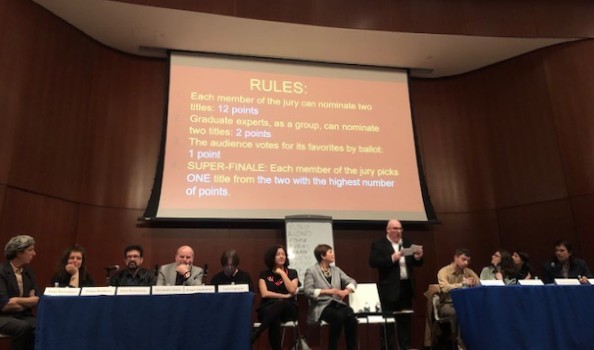 Jurors listen as Mark Lipovetsky reads the rules of Super-NOS. a man reading from a note while people are sitting next to him