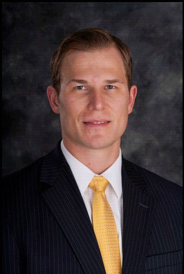 Neil Duncan in a dark blazer with a yellow tie and white button down shirt