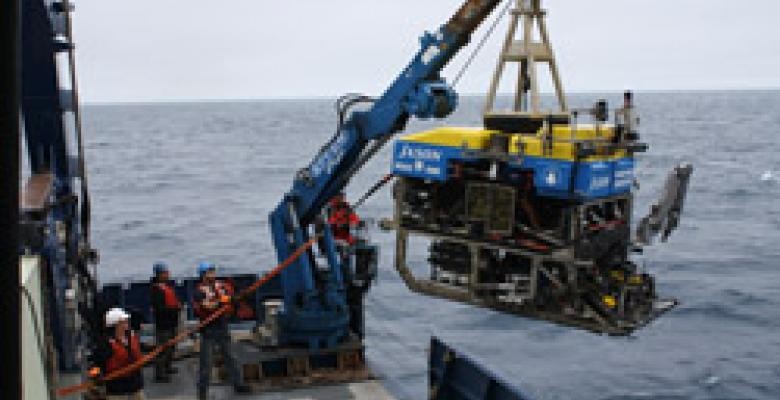 Crew members prepare the remotely operated vehicle Jason to dive to Axial Seamount. (Bill Chadwick, Oregon State University) Large machine being lowered into ocean