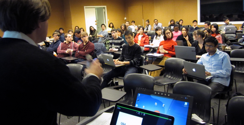 Looking over the shoulder of a professor speaking to a group of students 