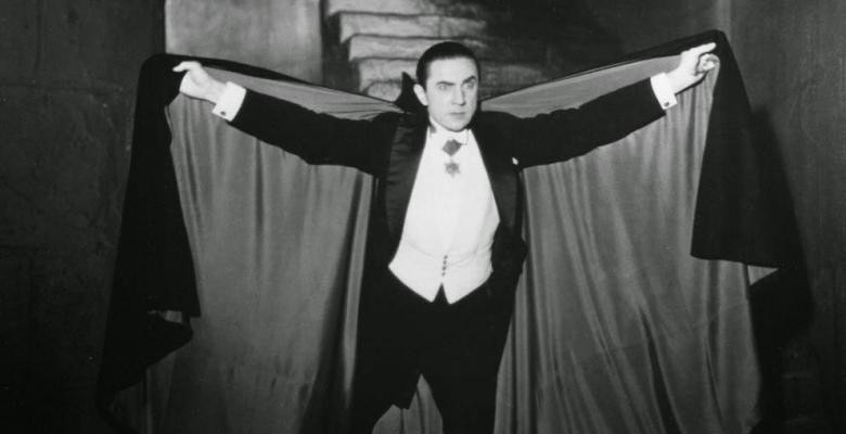 In a black-and-white image, actor Bela Lugosi spreads a black cape wide, portraying Dracula in Tod Browning’s 1931 film.