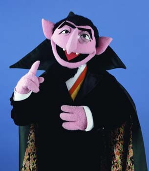 Sesame Street's vampire-inspired Muppet Count von Count wears a black cape and grins into the camera