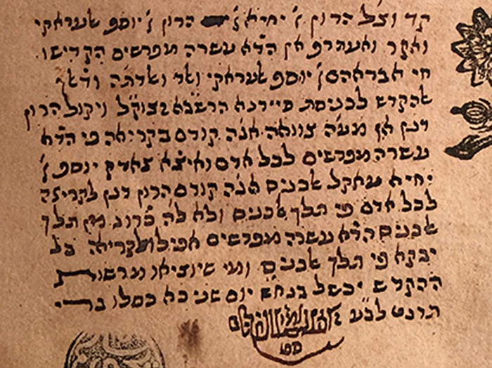Several lines of Hebrew txt run across an old piece of paper, part of a leather-bound book.