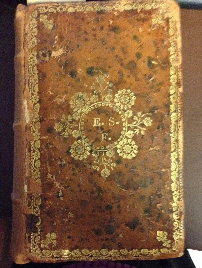 A leather-bound book with elaborate gold lettering and floral motif