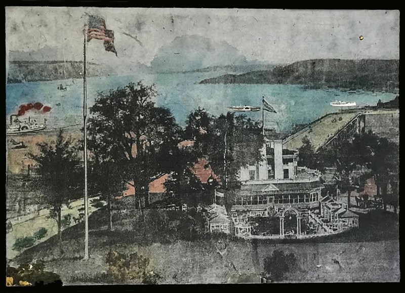 The Historical Claremont Inn. Art by Michal Nachmany A mixed media landscape of an ornate building and grounds, with an American flag on a flagpole in the foreground and a river in the background