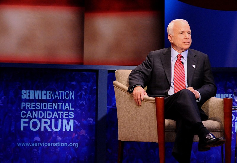 Sen. John McCain at the 2008 presidential candidates forum in Lerner Hall hosted by ServiceNation, a coalition of organizations that encourage civic engagement. John McCain sits in a chair on a stage next to a placard that reads "Service Nation Presidential Candidates Forum."