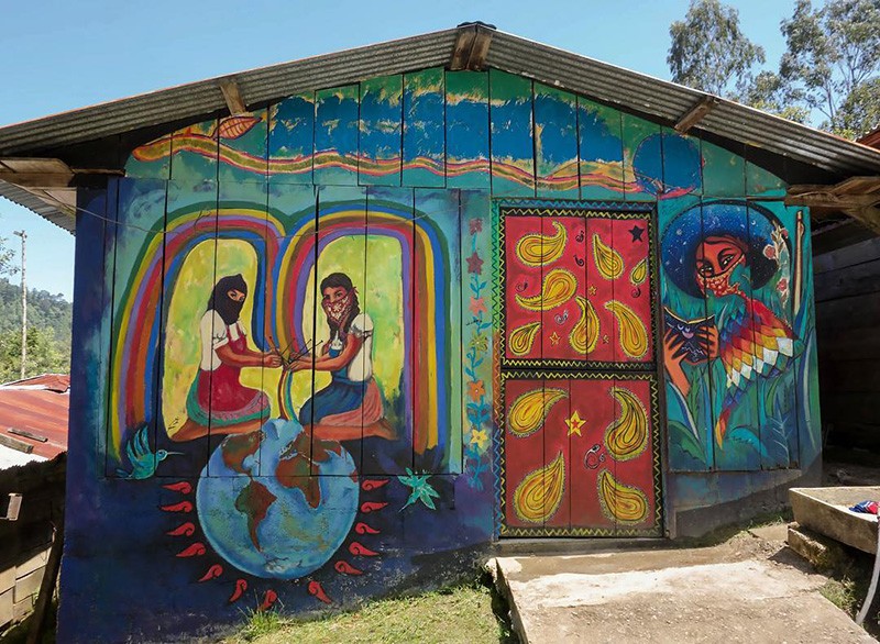This mural, which the Center for the Study of Social Difference used on the poster for its September conference, was painted by villagers in the Chiapas region of Mexico, an area largely controlled by Zapatistas, a revolutionary group. It was photographed by Lorie Novak, an artist, NYU professor and visiting fellow at the center. The facade of a small building is covered by a colorful mural depicting two women, kneeling and facing each other. The women stretch their hands toward each other.