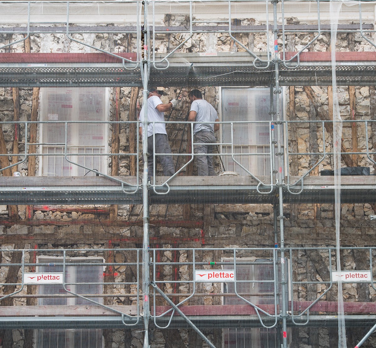 Photograph of workers on scaffolding re-facing a building