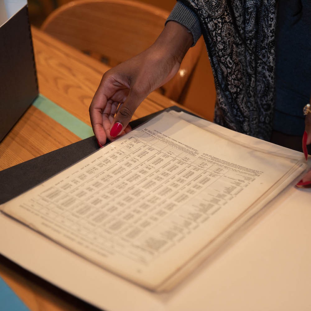 According to Sylverain, “There is an intimacy in reading, touching and experiencing the papers of figures like Hubert Harrison and Amiri Baraka. You are in a deep, personal conversation with their work and their accomplishments.” A women with red nails holding an old ledger