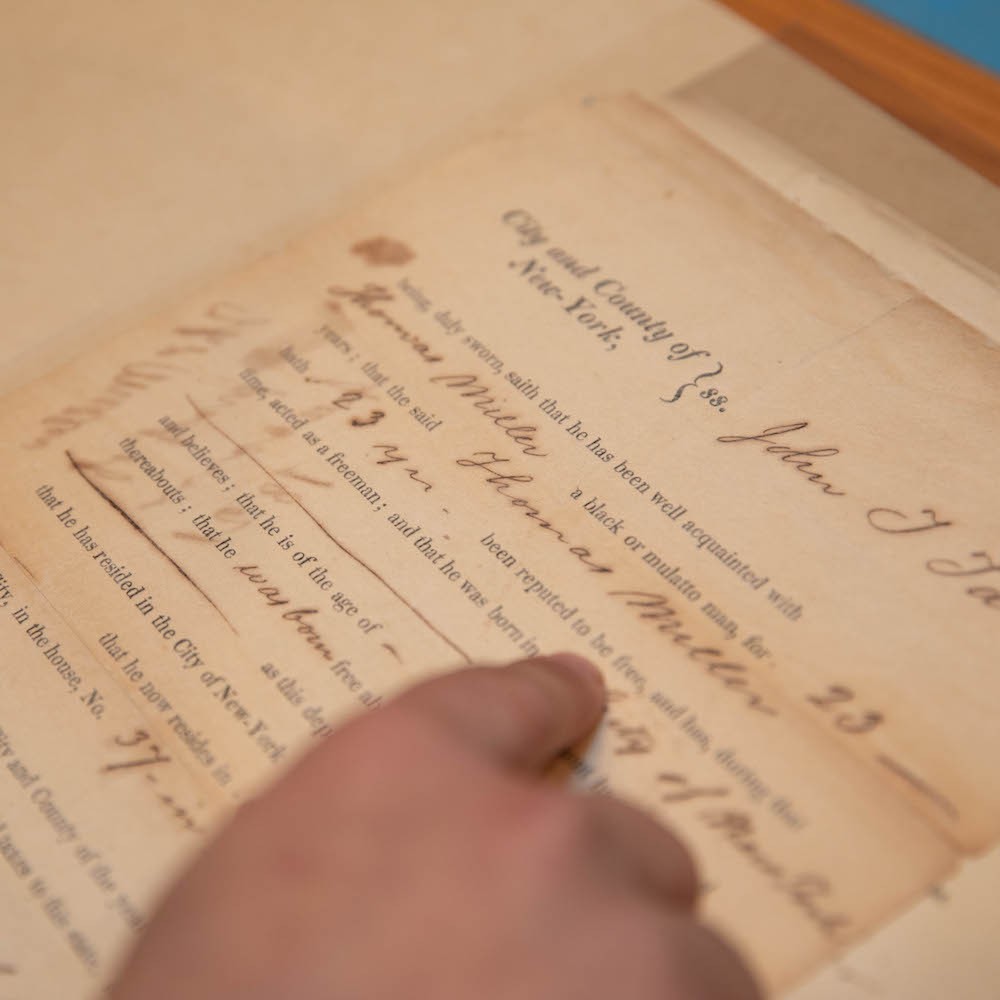 In this photo, Song is looking at the Plimpton Slavery collection, which he plans to incorporate into his Columbia historical tour app to help people “have a better understanding of not just the realities of slavery, but also how memories of enslavement were preserved—in this case by wealthy white philanthropists like George Plimpton.” Hand pointing to the word free on an old document