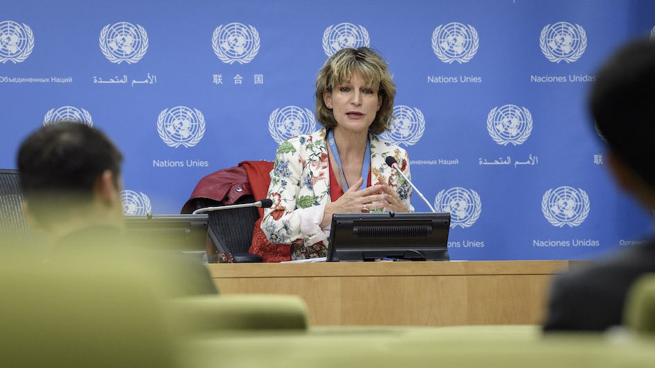 Woman speaking to an audience with the United Nations logos behind her