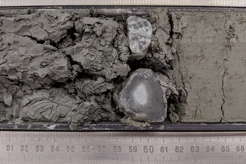 Dropstones found in a sediment core are an indicator of ice sheet variability. Photo by Jenny Middleton A close-up shot of dropstones coming out of sediment with a ruler underneath to measure the stones.