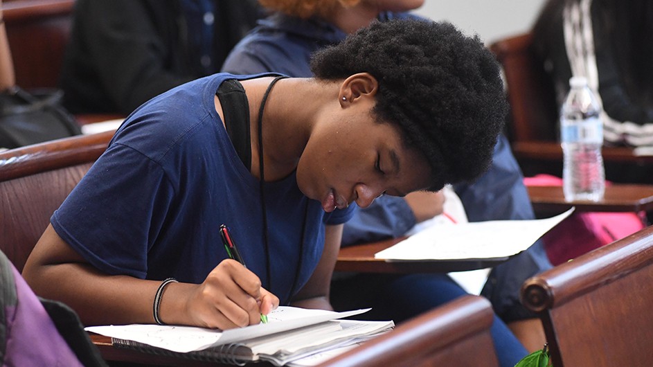 A high school student in the 2019 Double Discovery Center program. Photo: Eileen Barroso Teenage girl at a classroom desk writing in a notebook