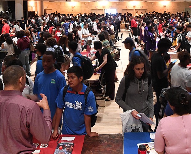 Crowd of teenagers in an auditorium for a college fair