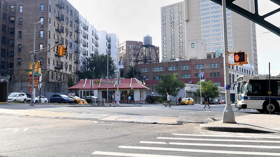 The street corner of 125th and Broadway where a McDonald's restaurant sits in front of warehouses and residential buildings.