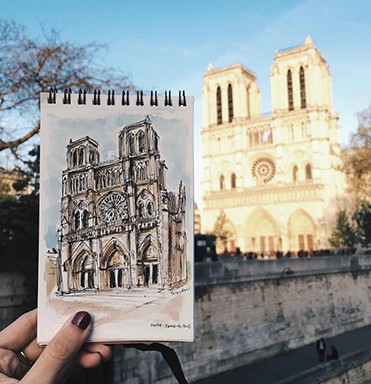 Sketch of Notre Dame being held up in front of the actual Notre Dame building