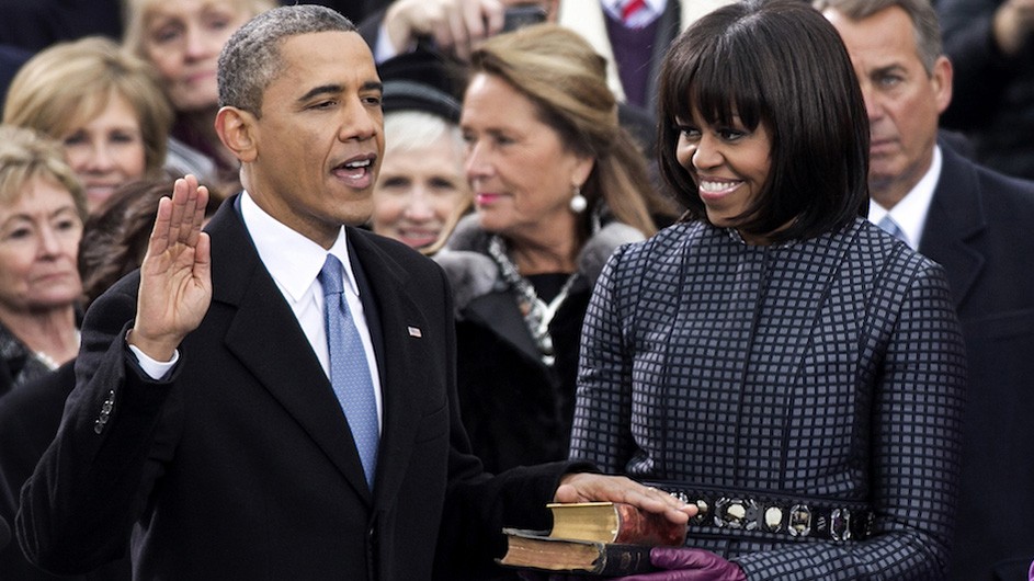 President Barack Obama and First Lady Michelle Obama at his second inauguration, January 21, 2013. President Barack Obama raises his right hand and he and First Lady Michelle Obama place a hand on a bible.