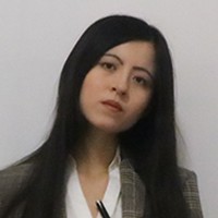 Headshot of a lwoman with long dark hair, in a grey suit and white shirt. 