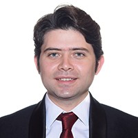 Man with short, dark hair in a dark suit and tie