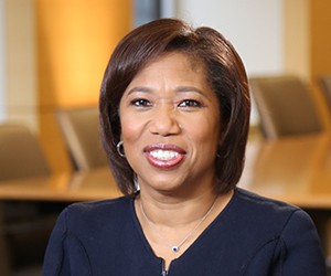 Kim Lew Headshot of a dark-skinned woman with medium-length dark hair and a black top