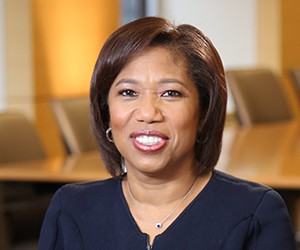 Headshot of a dark-skinned woman with medium-length dark hair and a black top