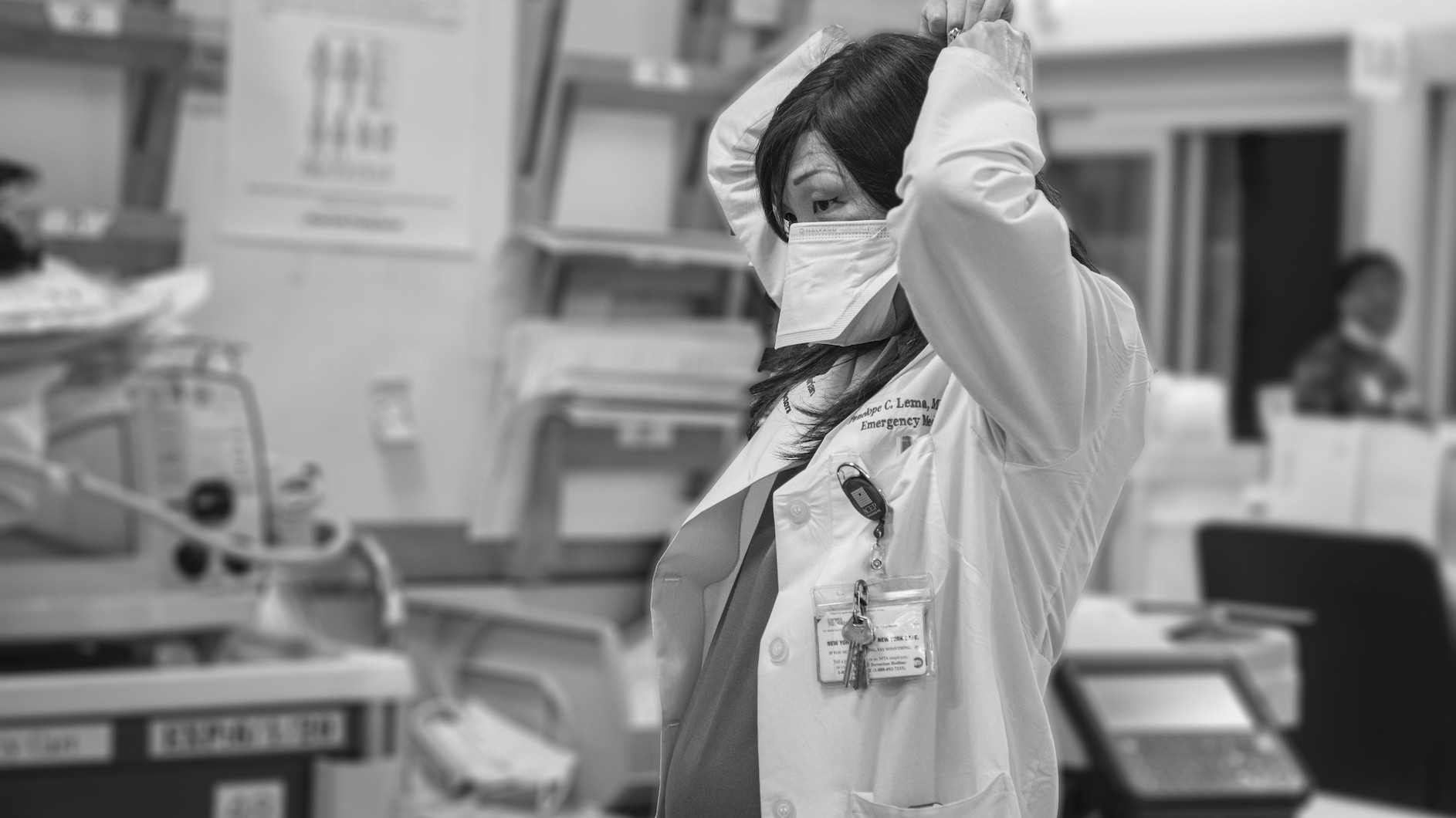 Dr. Penelope Lema putting on PPE in NewYork-Presbyterian Hospital/Columbia University Irving Medical Center (CUIMC). Photo credit: Jennifer O'Rourke, courtesy of CUIMC Black and white photo of doctor who is pregnant putting her face on in the hospital