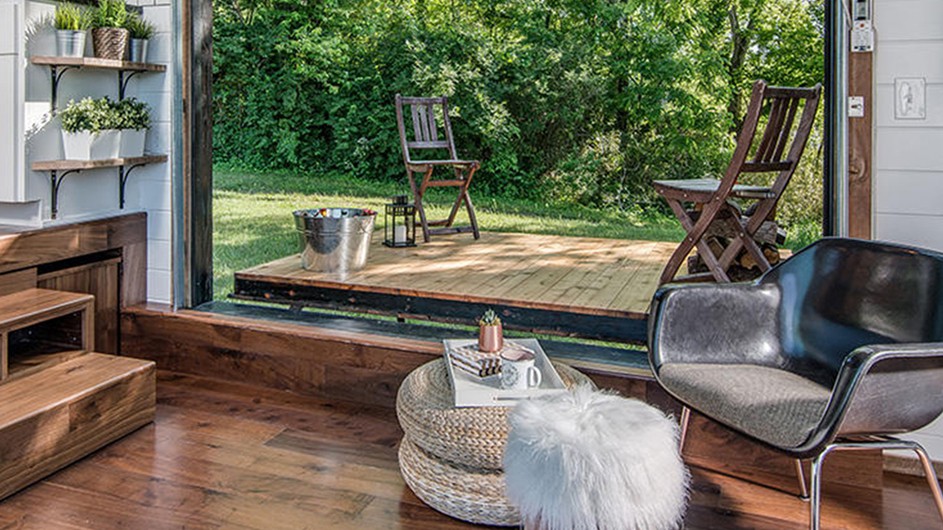 Living area. Nashville, Tennessee. Building and interior design by David Latimer for New Frontier Tiny Homes. Photography by StudiObuell. An interior of a home office with a window onto the outdoors with greenery.