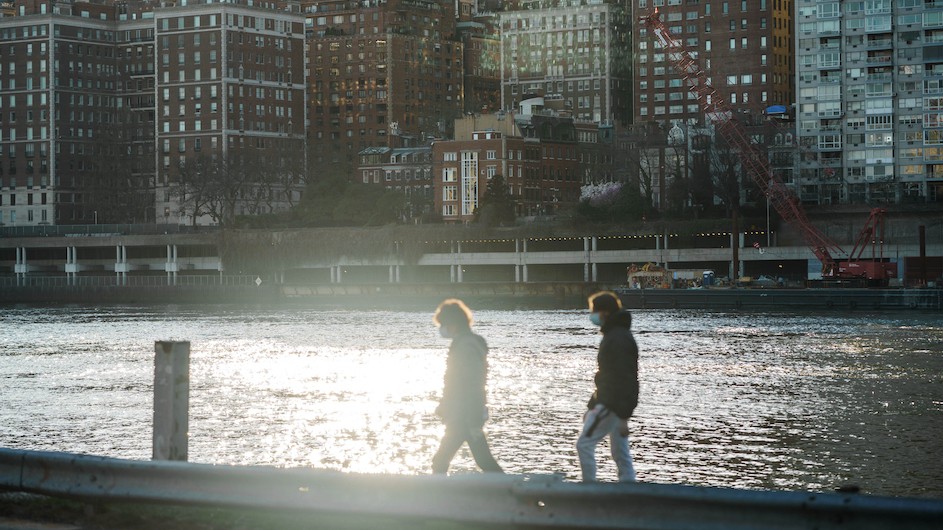 People with masks walking along the East River