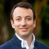 Adam Pritzker Man with short dark hair, in a dark blue sweater and white shirt